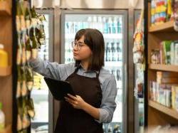 Young store clerk sorting and counting inventory on shelves